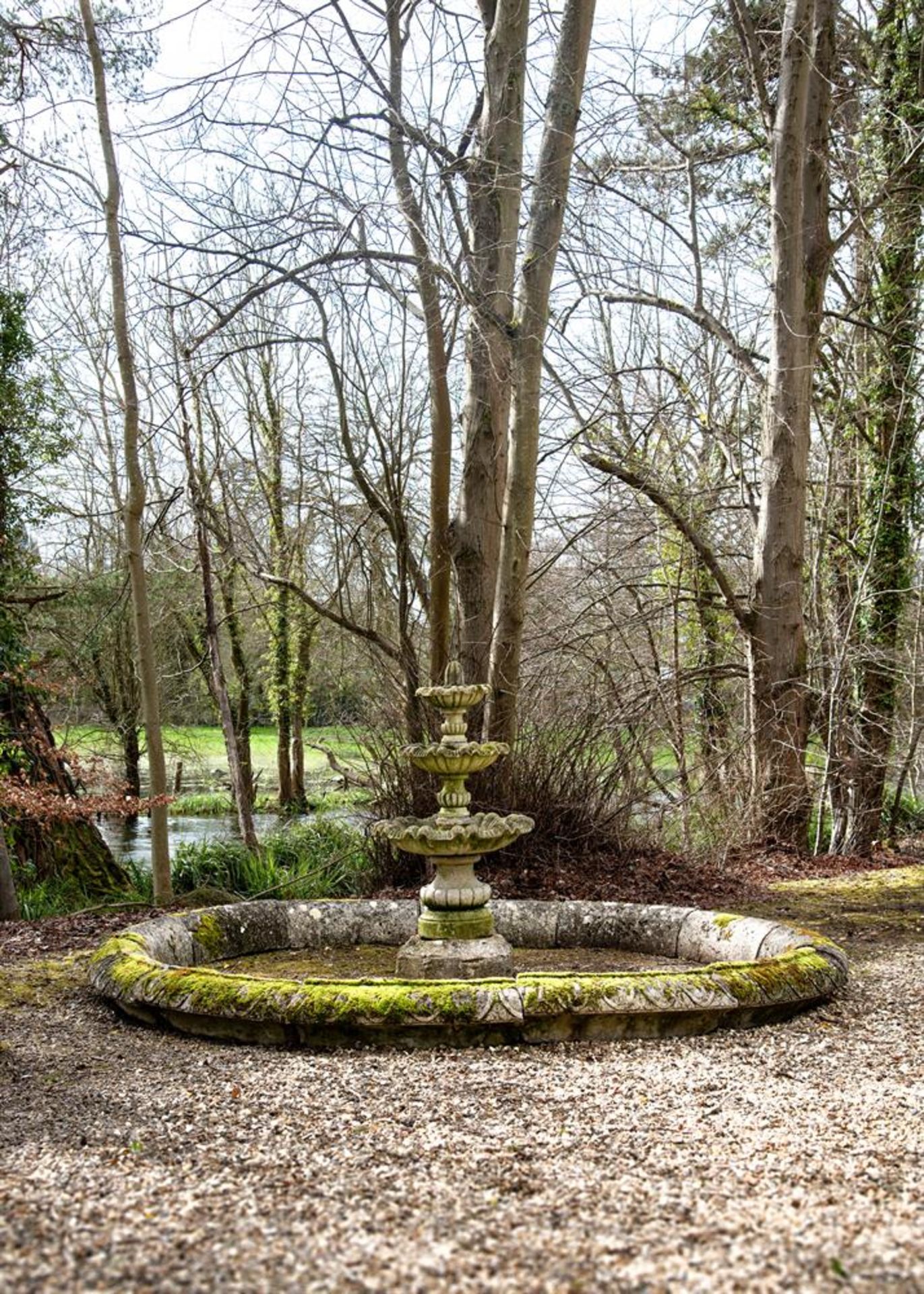 A STONE COMPOSITION POND SURROUND AND TRIPLE TIERED FOUNTAIN, ATTRIBUTED TO AUSTIN AND SEELEY