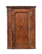 A GEORGE II BURR WALNUT, FEATHERBANDED AND GILT GESSO CORNER CUPBOARD, CIRCA 1730