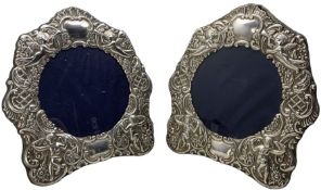 Pair of silver photograph frames with circular apertures and embossed with angels and cherubs