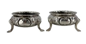 Pair of Victorian Scottish silver circular salts with embossed decoration and triple shaped supports