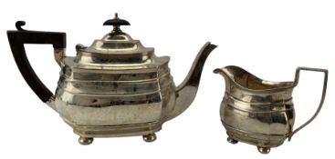 Silver rectangular teapot of panel sided design with ebonised handle and lift on compressed bun feet