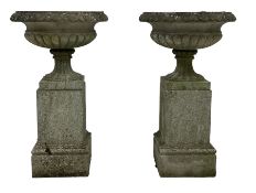 Pair of cast stone garden urns on plinths
