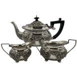 Late Victorian silver three piece tea set embossed with panels of flower heads and scrolls on ball f