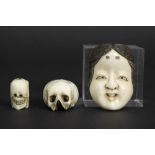 three old smalls in bone : a Japanese mask, a skull and a sculpture with on one side the face of