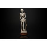 sculpture in bone depicting a skeleton with axe - on a wooden base || Sculptuur in been met de