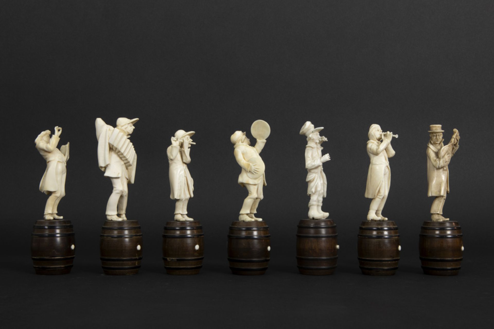 set of seven small antique figures in ivory, each standing on a wooden barrel - depicting a band - Image 4 of 6