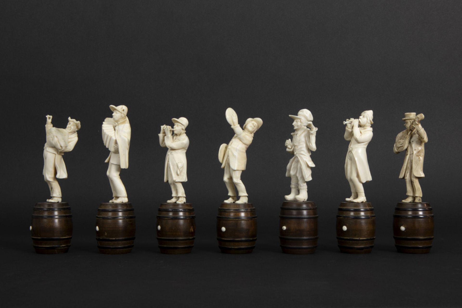 set of seven small antique figures in ivory, each standing on a wooden barrel - depicting a band - Image 3 of 6