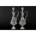 pair of antique claret jugs in clear cut crystal with mountings in marked silver || Paar antieke