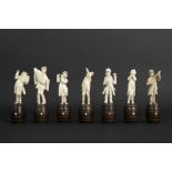 set of seven small antique figures in ivory, each standing on a wooden barrel - depicting a band