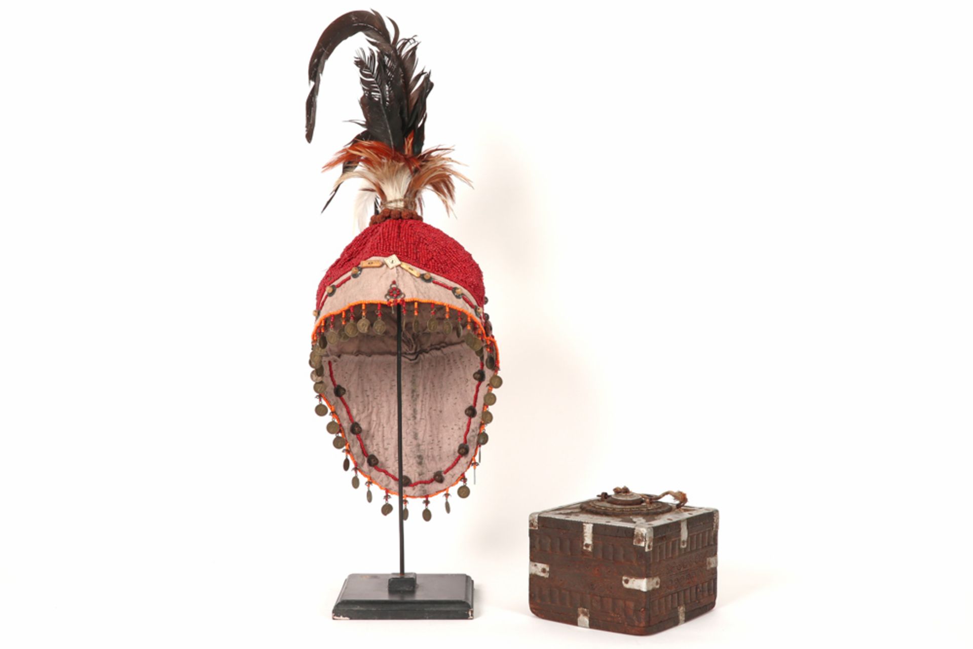 two oriental collector's items : an opium box and a hat in textile with feathers and beads || Twee