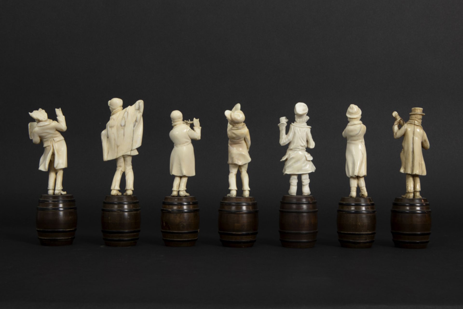 set of seven small antique figures in ivory, each standing on a wooden barrel - depicting a band - Image 5 of 6