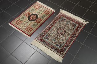 two small hand knotted rugs in silk amongst which a Persian Qom || Lot van twee kleine handgeknoopte