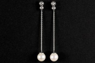 pair of quite long earrings in white gold (18 carat) each with a pearl and with 0,22 carat of very