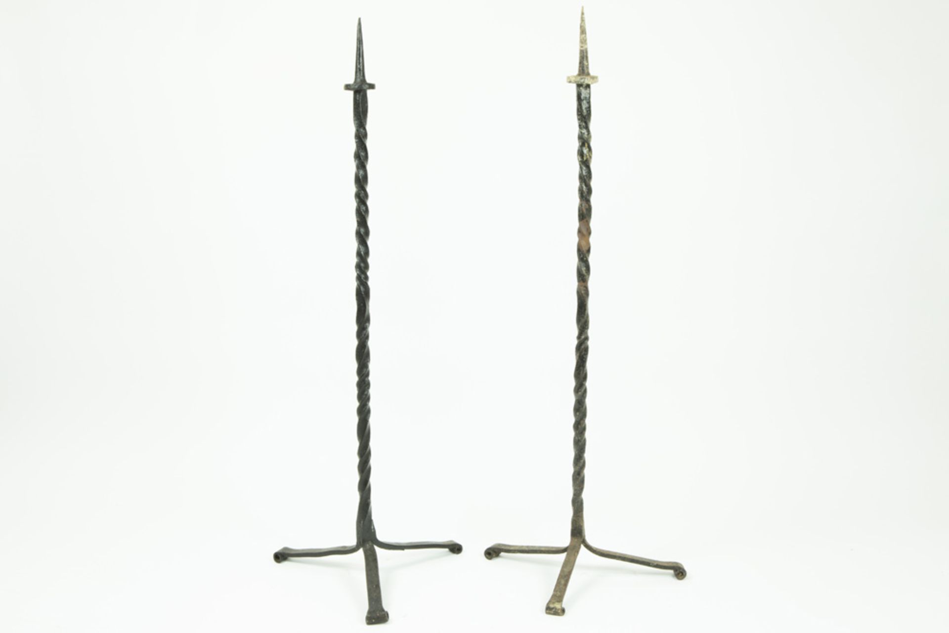 two quite big candlesticks in wrought iron || Lot van twee vrij hoge kandelaars met driepikkelpoot