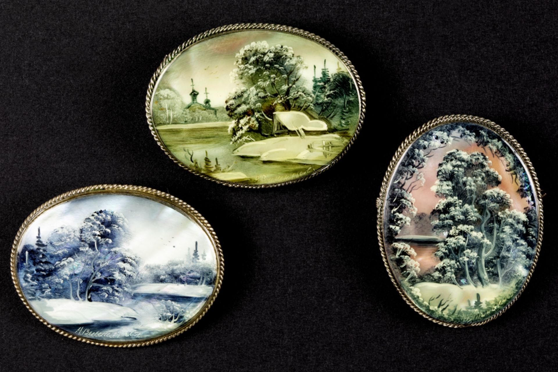 three oval brooches each with a plaque in mother of pearl/shell with a painted landscape || Lot