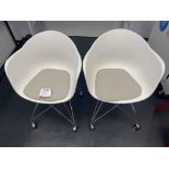 Two white plastic tub chairs on wheels
