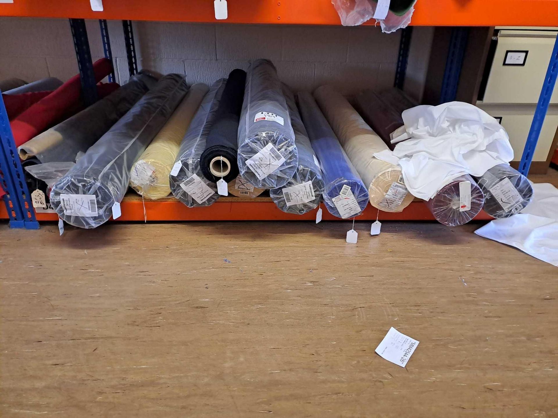 Contents of shelf to include 14 rolls of various coloured fabric