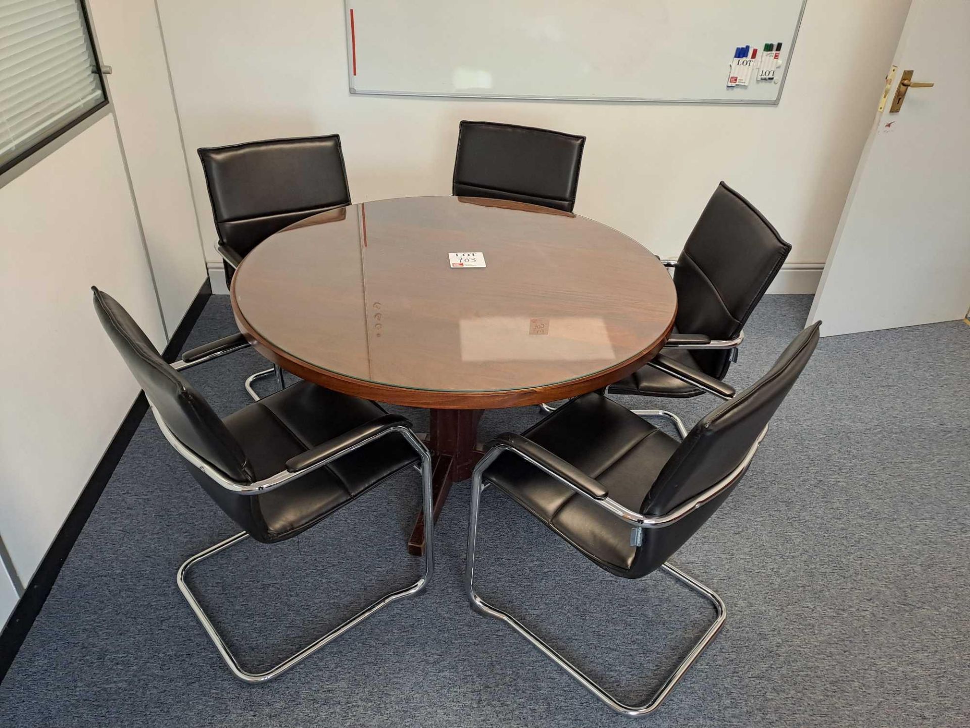 Circular glass topped wooden table, five black leather effect chairs