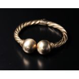 The bangle is made of twisted gold wires and has round spheres at the end.The spheres have a