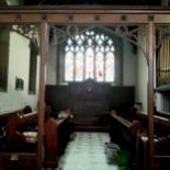 A Victorian carved oak ecclesiastical rood screen with three open archways leading to the chancel