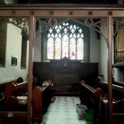 A Victorian carved oak ecclesiastical rood screen with three open archways leading to the chancel