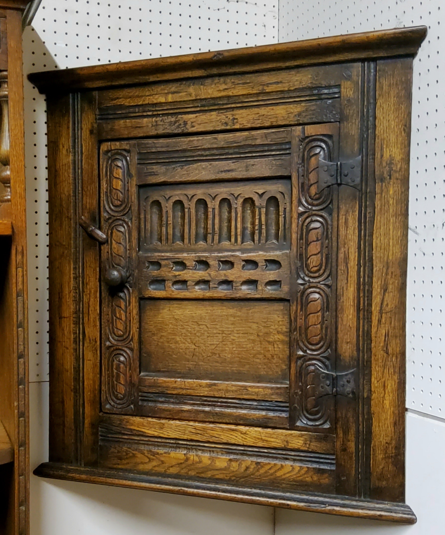 A Titchmarsh & Goodwin style oak corner cabinet, the fielded panelled door carved with lunettes,