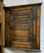 A Titchmarsh & Goodwin style oak corner cabinet, the fielded panelled door carved with lunettes,
