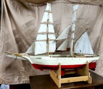 A large scratchbuilt wooden pond yacht, called Flame, with masts, sails and rigging, with painted