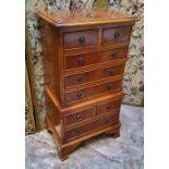 A small reproduction yew chest on stand, the crossbanded oversailing top flanked by fluted columns