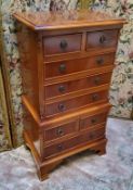 A small reproduction yew chest on stand, the crossbanded oversailing top flanked by fluted columns