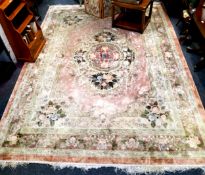A large Chinese woolen rug, with large central boss with floral motifs, on a pink and terracotta