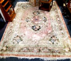 A large Chinese woolen rug, with large central boss with floral motifs, on a pink and terracotta