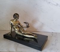 Art Deco, a silvered bronze, a lady with a bird, reclining, black rectangular marble base, 22cm wide