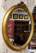 A Victorian oval parcel gilt mirror surmounted with floral swags, bevelled edge looking glass 67cm
