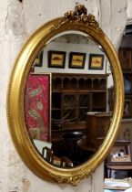 A Victorian oval parcel gilt mirror surmounted with floral swags, bevelled edge looking glass 67cm