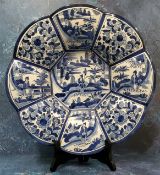 A Delft style lobed circular dish, in underglaze blue, with stylised figure in a landscape to