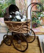 A wrought iron and woven wicker dolls pram / stroller; basket with decorative artificial flowers