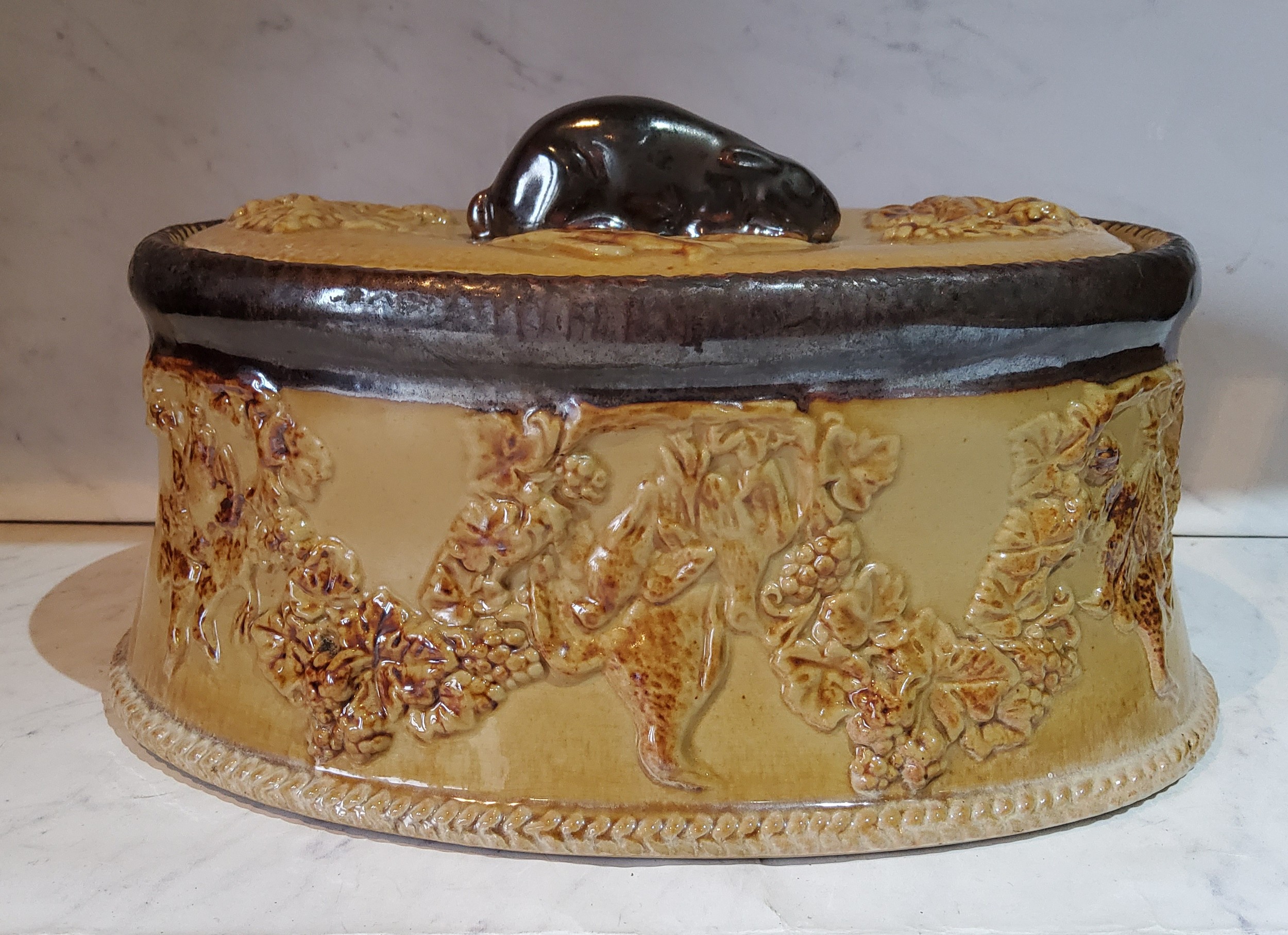 A 19th century salt glazed game tureen and cover, the sides in relief with hanging game, hare