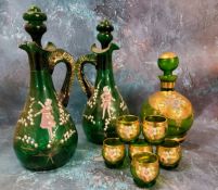 A pair of Mary Gregory green glass decanters, painted with a boy and a girl amongst snowdrops,