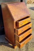 A small burr walnut bureau, fall front revealing tooled leather writing surface above four