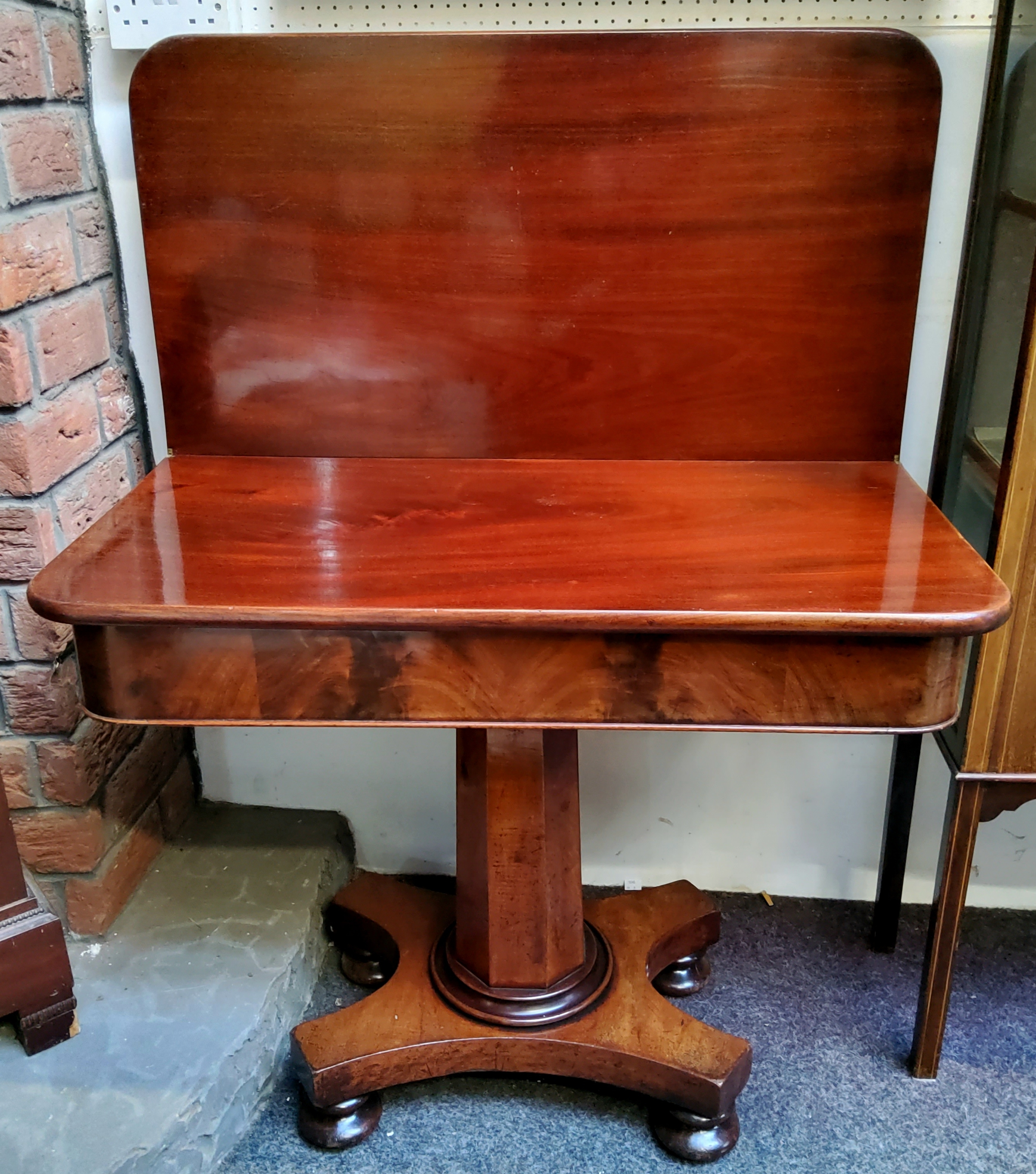 A William IV flamed Cuban mahogany tea table, hinged, rotating surface above octagonal column, bun