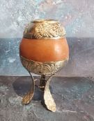 A South American silver coloured metal mounted calabash gourd mate cup, loft legs, 14cm high