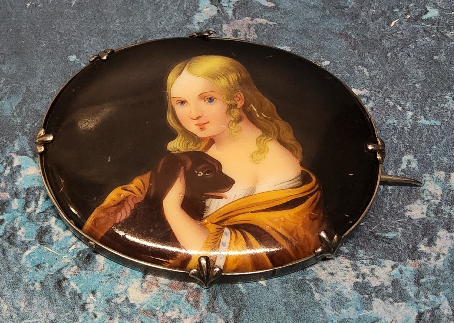 A white metal mounted hand painted brooch depicting a young girl and her dog, 5.3 x 6.5cm