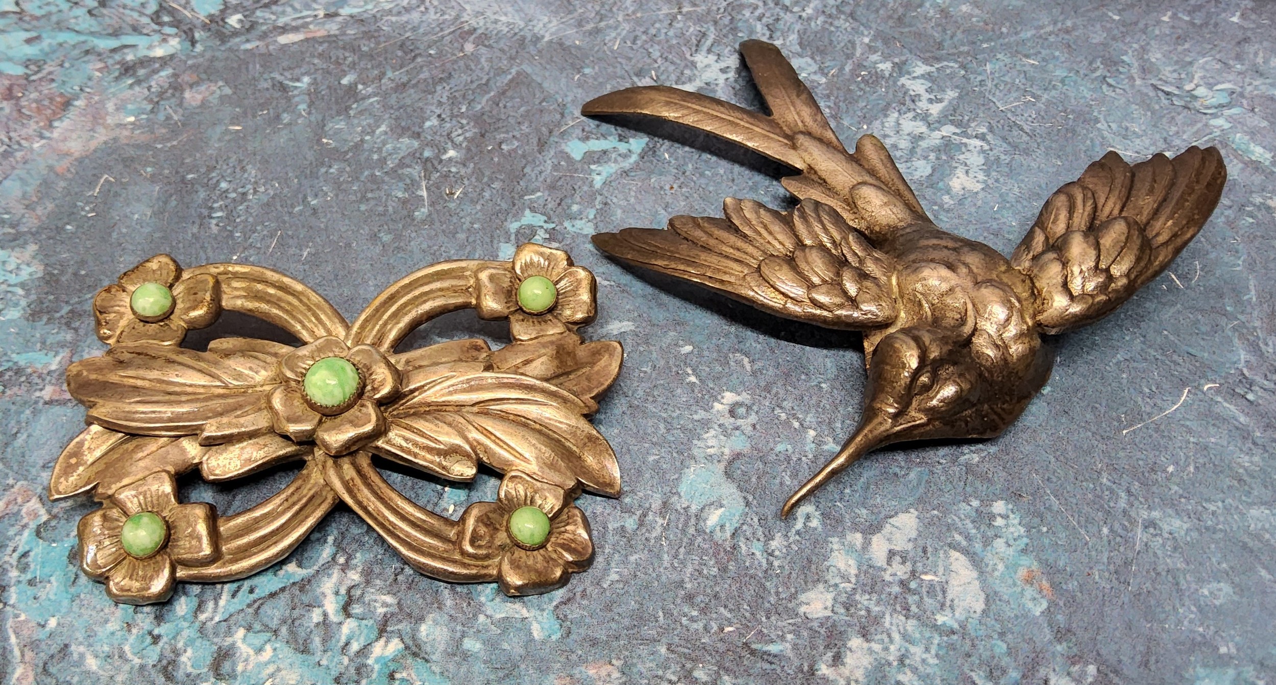 A white metal brooch in the form of a flying humming bird; another decorative white metal brooch set