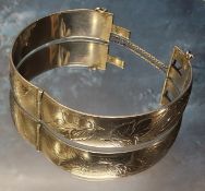 A silver hinged bangle, engraved & chased with foliage, clasp faulty, Harrod's Stores Ltd,