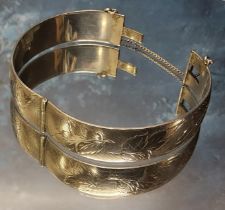 A silver hinged bangle, engraved & chased with foliage, clasp faulty, Harrod's Stores Ltd,