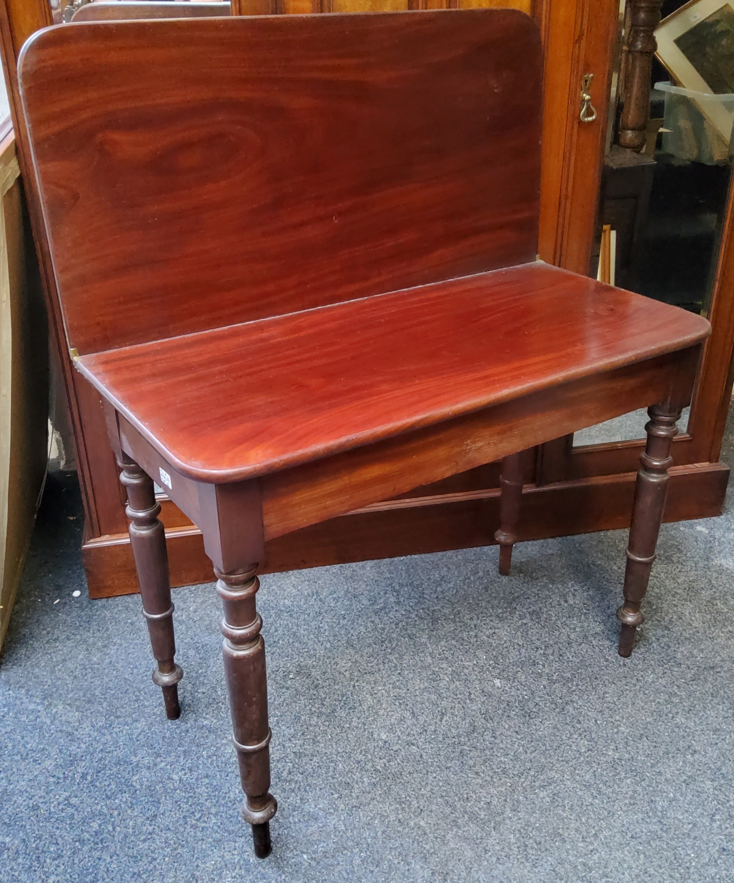 A 19th century mahogany folding tea table, rounded rectangular top, secret compartment, turned legs,