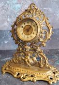 A Victorian brass mantel clock, the dial with Arabic numerals, pierced leafy scroll and cherub case,