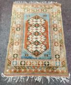 A Turkish Kazak rug with geometric panels in tones of olive green, terracotta and duck egg blue,