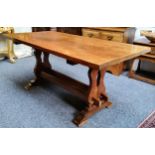 An English oak and elm trestle dining table, well figured top, pierced supports, twin central